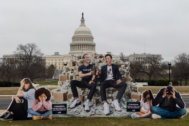 A protest outside US Congress depicts Zuckerberg and TikTok CEO toasting champagne on pile of cash.